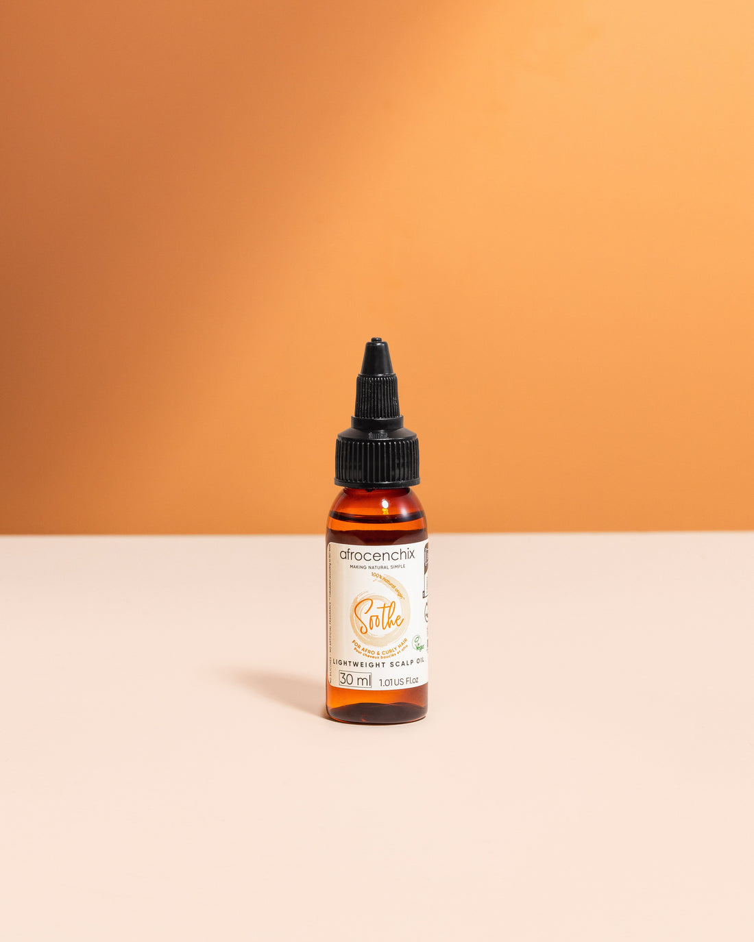 A bottle of Mini Soothe Natural Scalp Oil on a two-tone background.